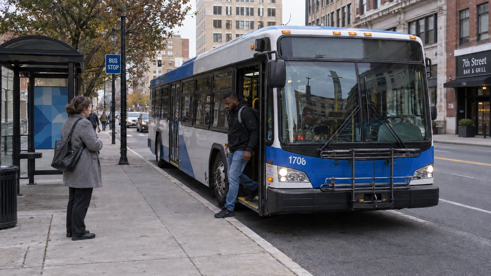 A passenger leaving a stopped city bus while another person waits on the sidewalk.