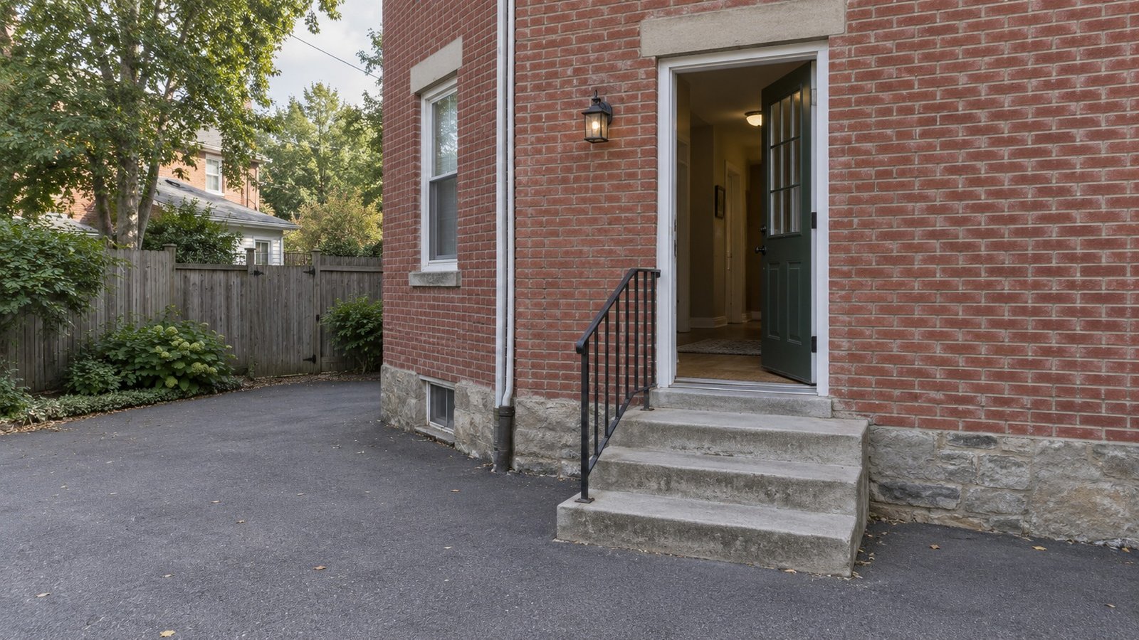 Follow the complete entrance route An open side door above a small landing, three exterior steps and a metal railing beside a brick home.