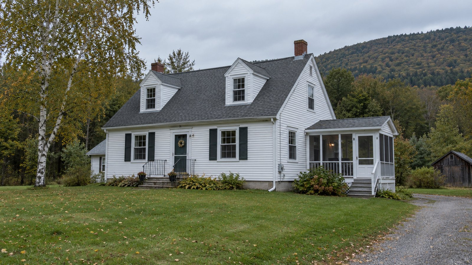 A home and its delivery approach White clapboard Cape house with two dormers, a screened porch and a gravel driveway