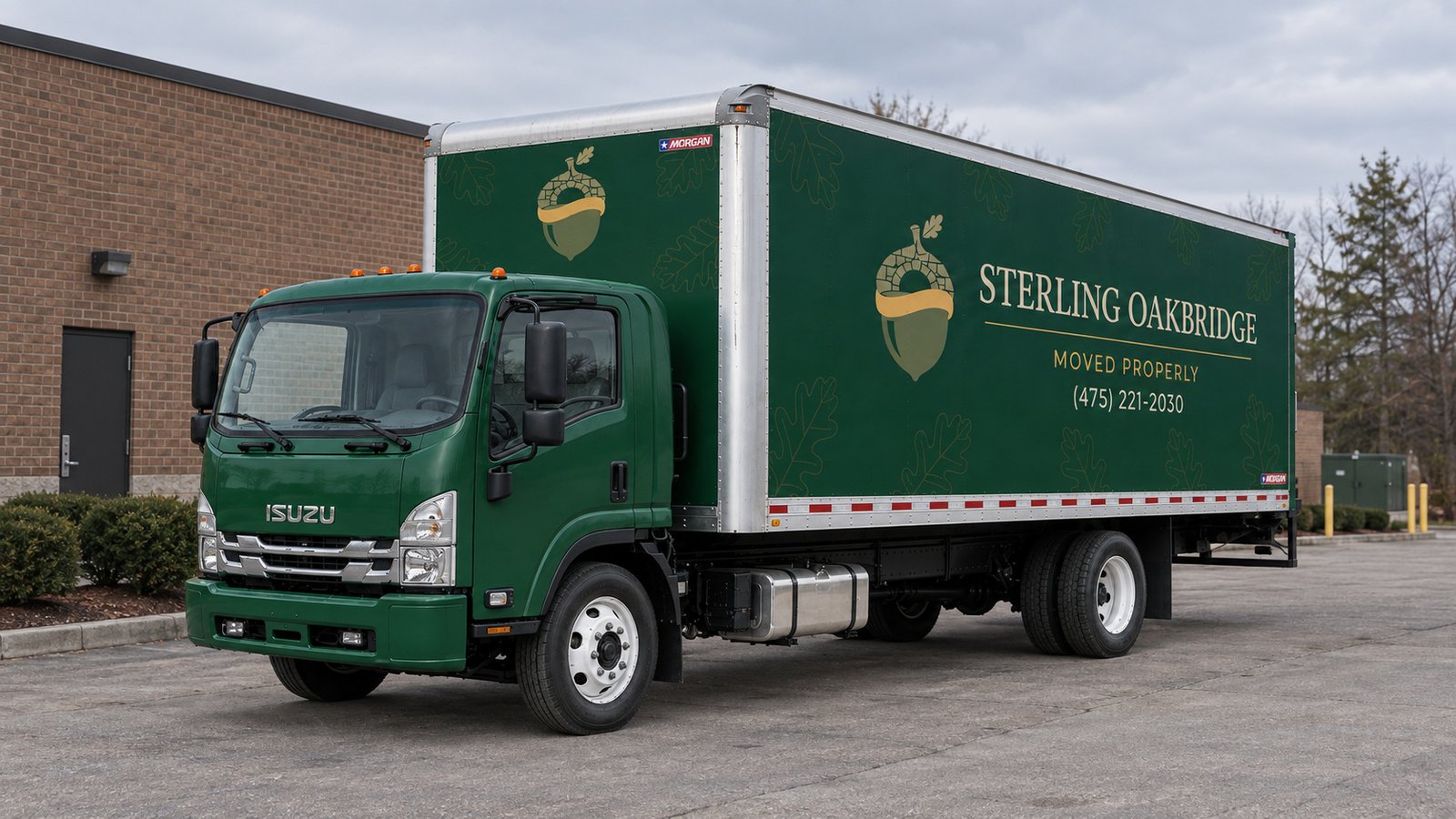 Confirm the truck position A whole green Sterling Oakbridge FTR26 truck viewed from the front quarter on a paved apron beside a brick building.