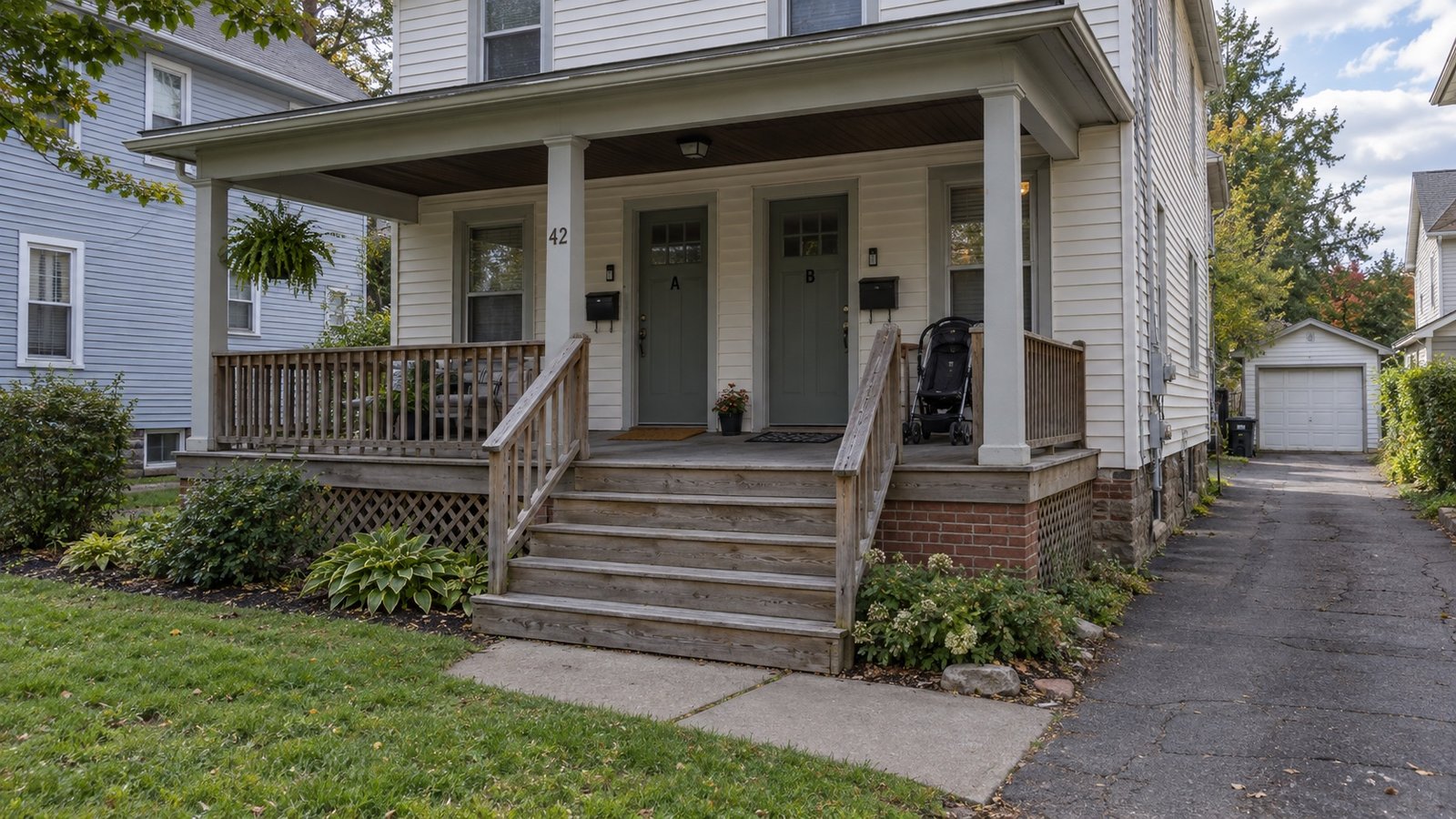 An older frame double with a shared porch and a narrow side driveway.