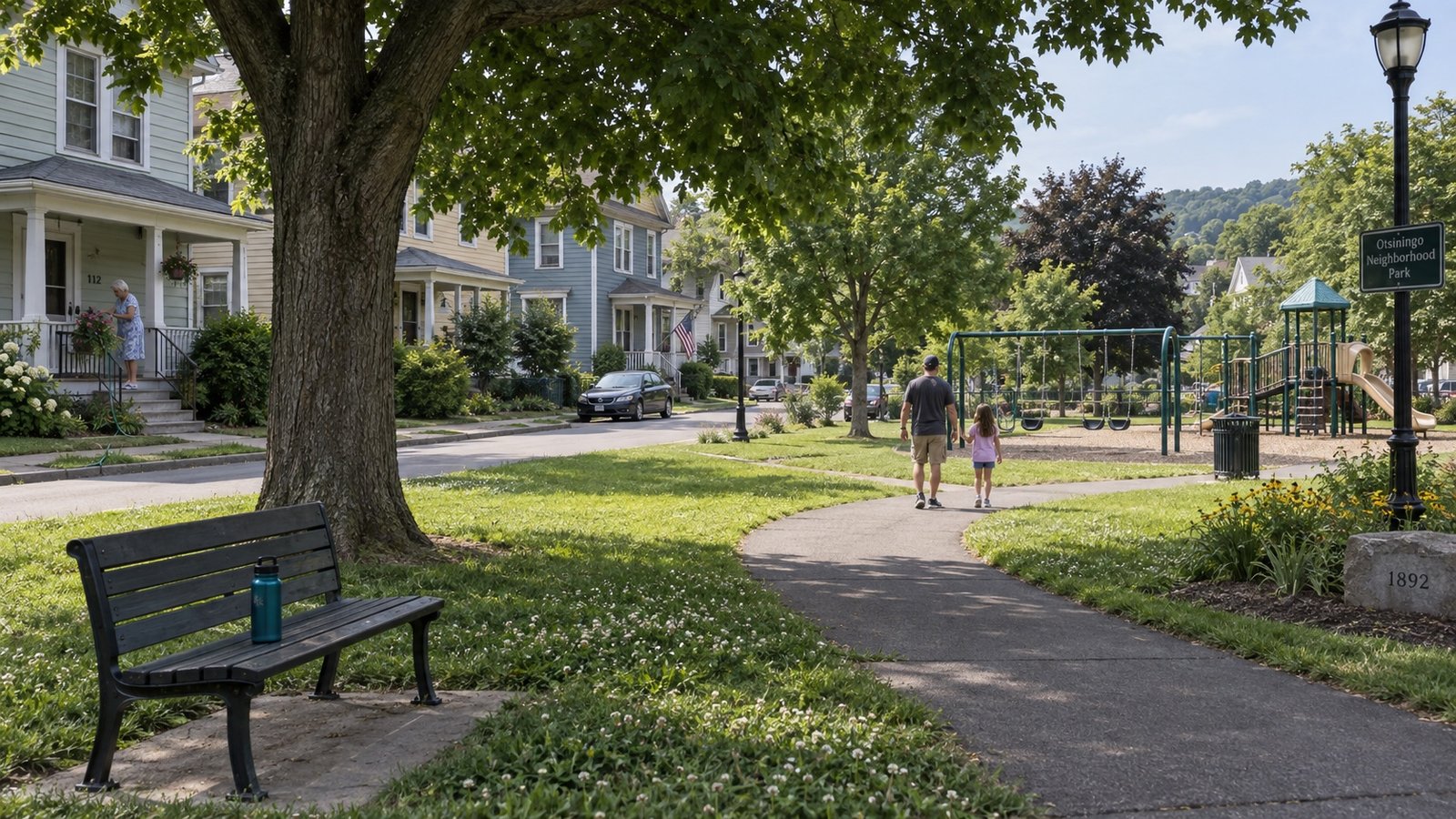A neighborhood street with a small park and older houses beyond.