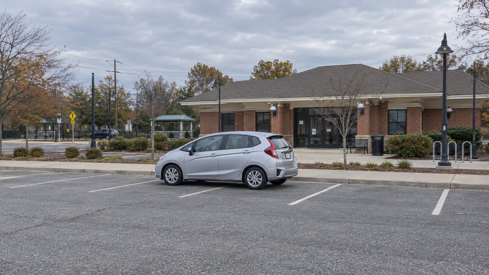 A whole unattended silver hatchback with closed doors and trunk in a marked parking bay.