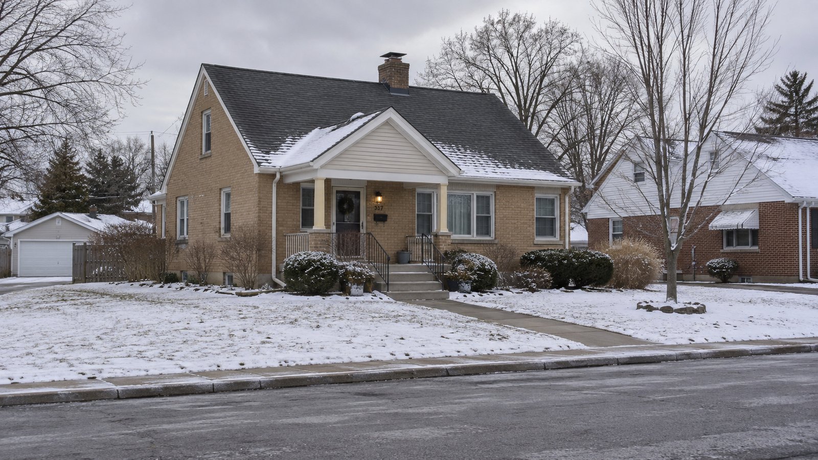 A complete brick bungalow with a cleared front walk and porch steps after light snow.