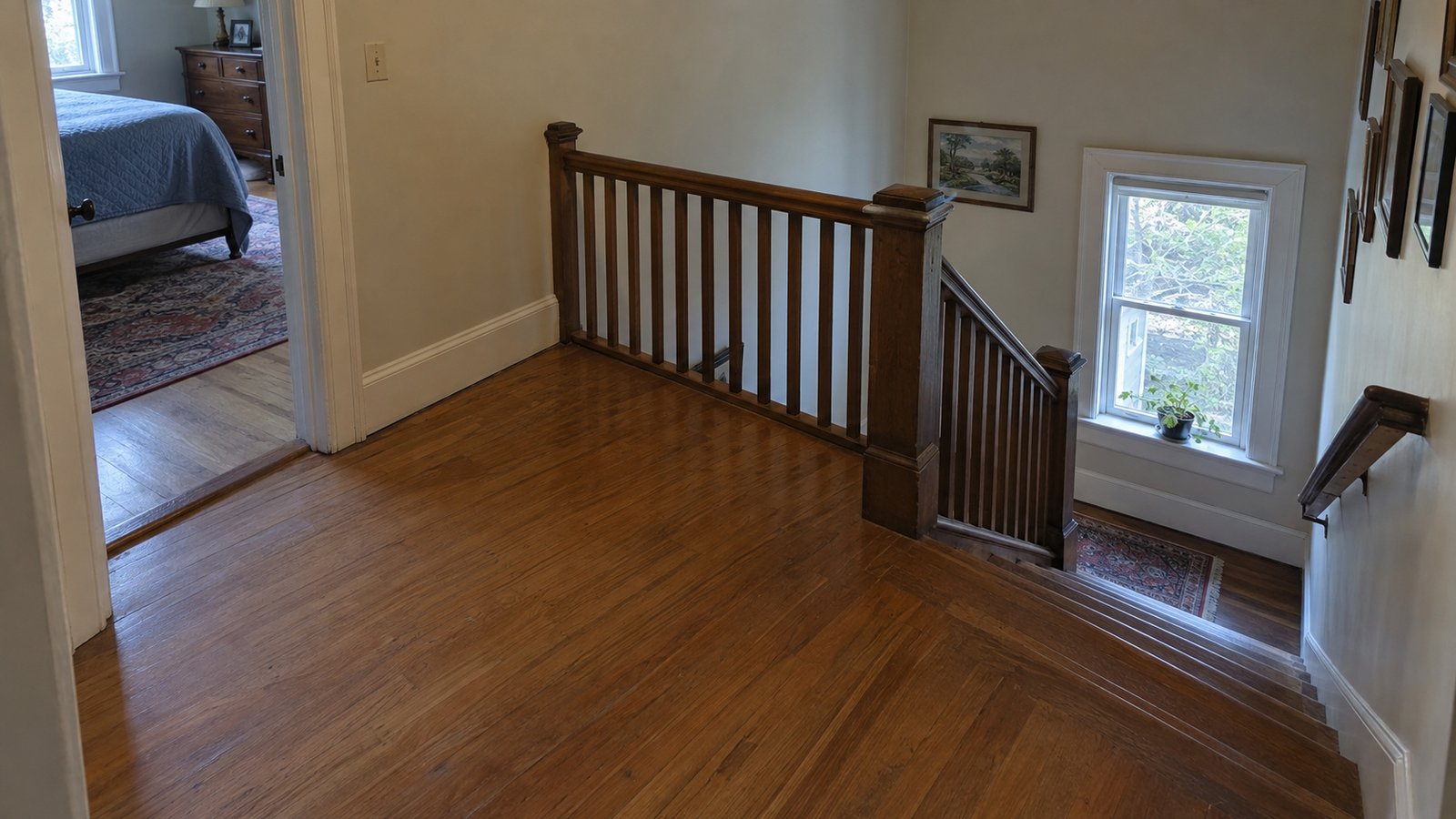 An upstairs wooden landing between a bedroom doorway and a straight staircase