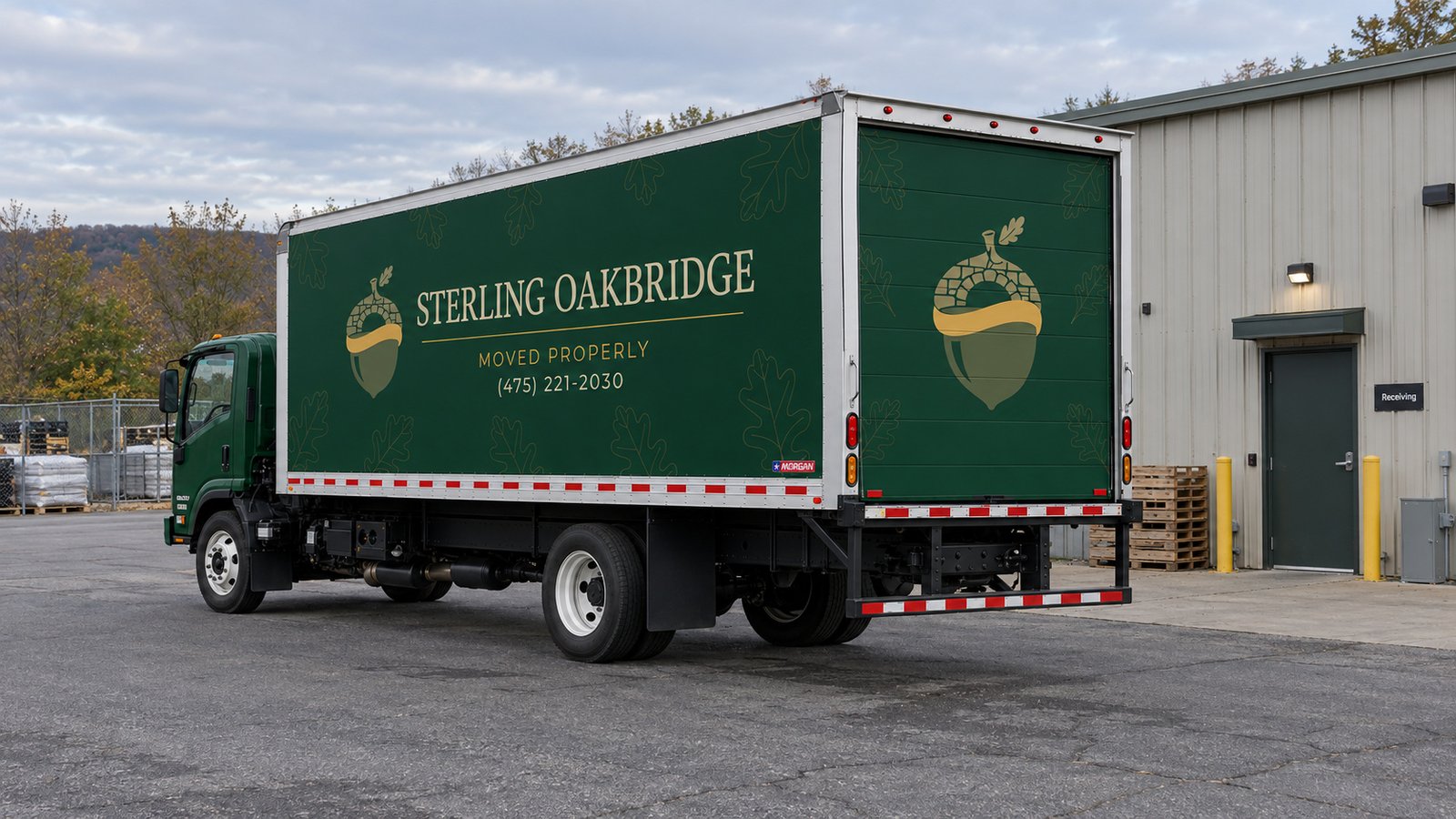 A dark green Sterling Oakbridge truck on a paved service apron beside a small commercial building