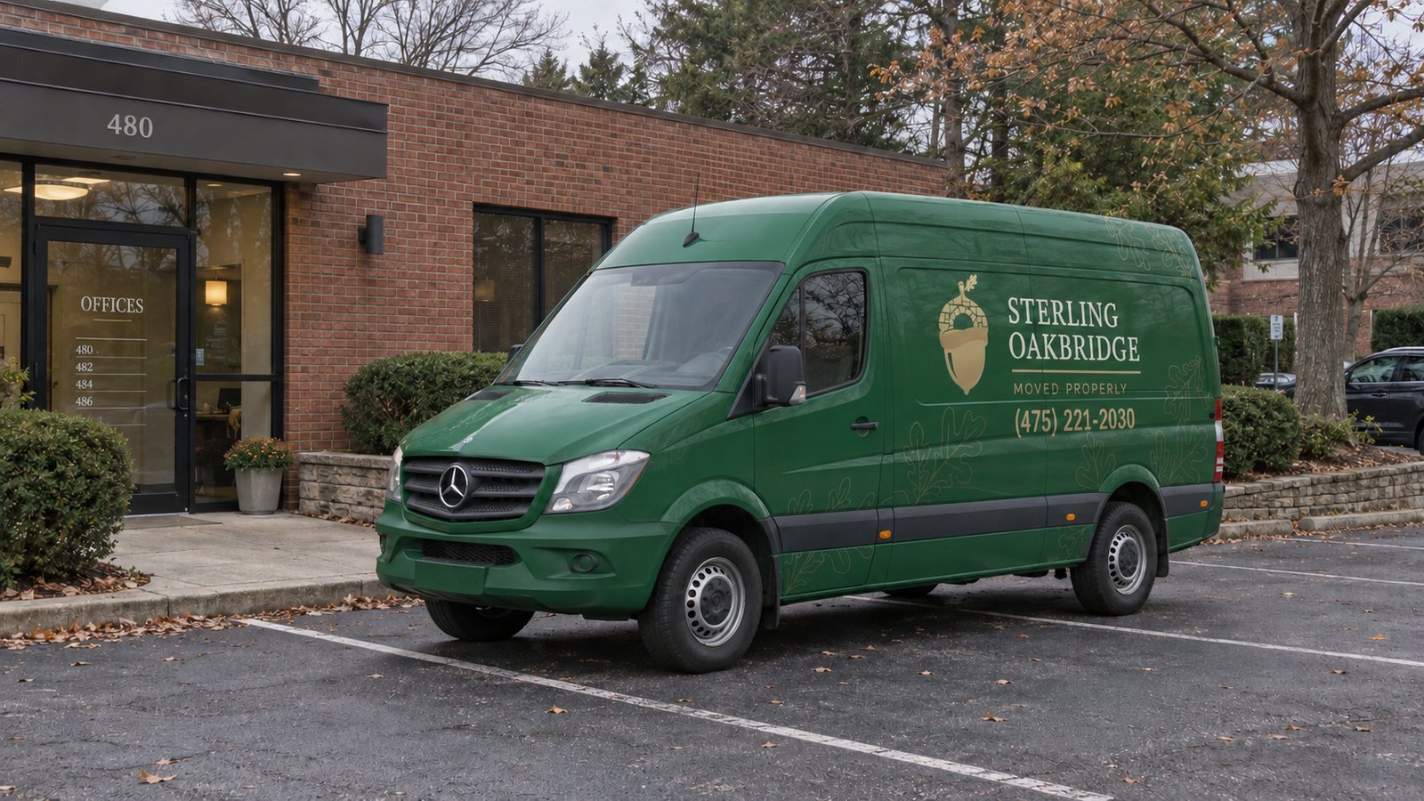 A private standing area Green Sterling Oakbridge Sprinter parked in a paved forecourt outside a low brick office building.