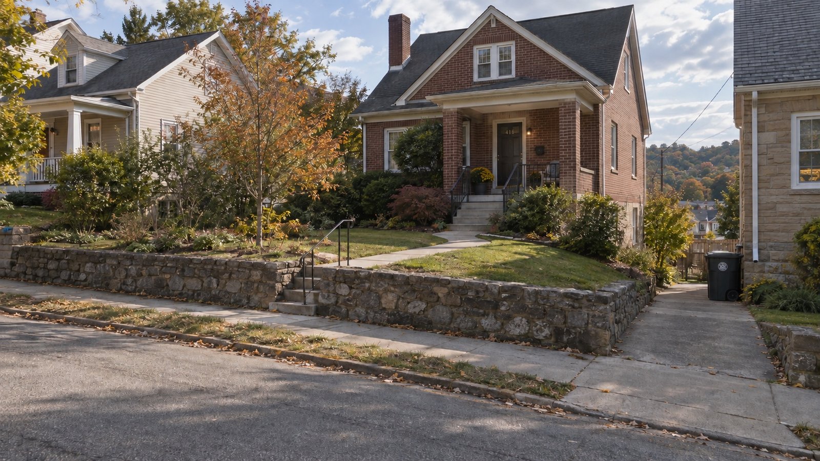 Wide street view of a brick hillside house, neighboring homes and the continuous stepped path to its porch