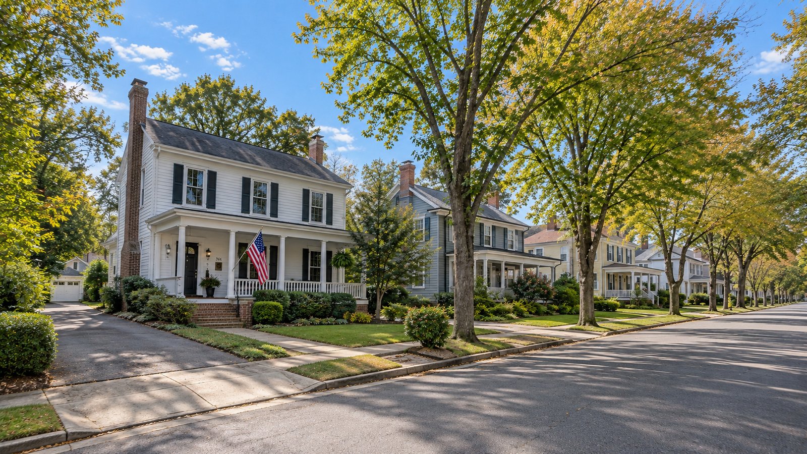 Review the receiving property White two-story houses, porches and driveways along a tree-lined residential street.