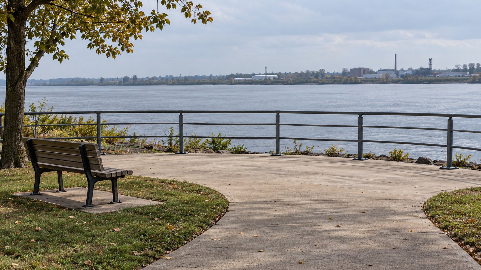 A river outing in the household week A curved concrete path opening onto a river overlook with a supported bench and an anchored metal railing.