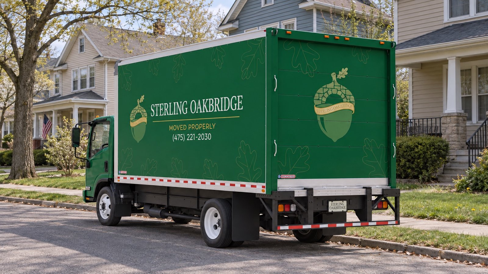 Green Sterling Oakbridge box truck with its rear door closed at a residential curb