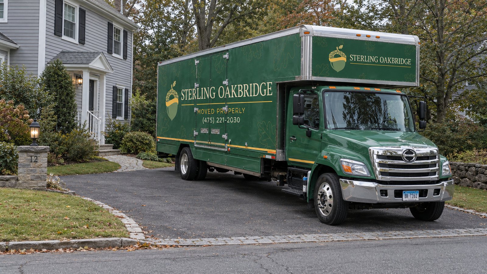 Plan the vehicle standing space A complete green Sterling Oakbridge Hino box truck parked on a paved private driveway beside a house.