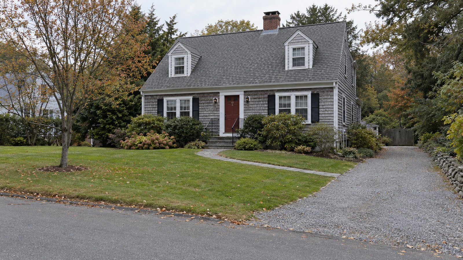 Review the receiving home A complete gray shingle Cape home with two dormers, front steps, a curved walk and gravel driveway.