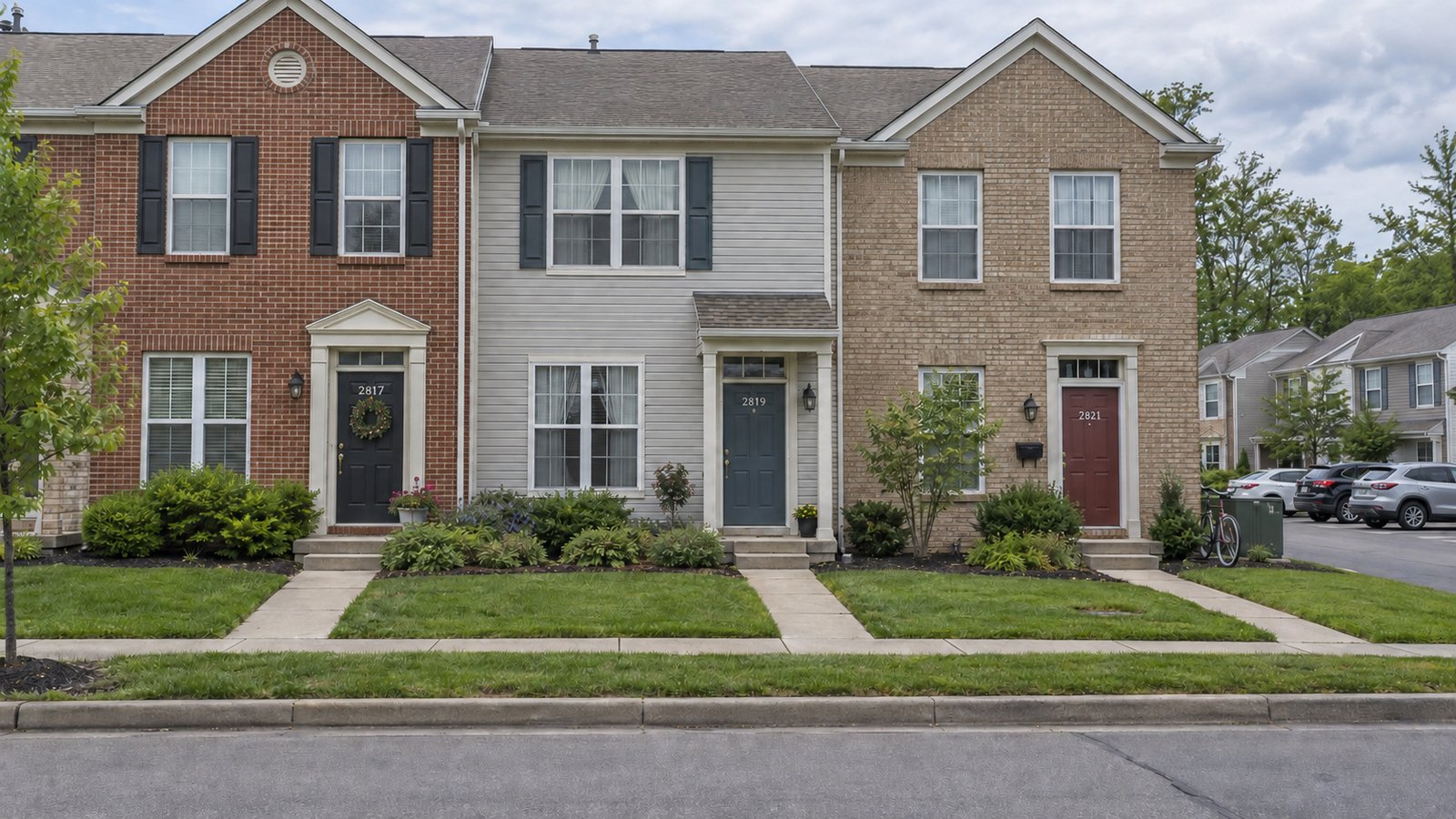 Separate entrances along a townhouse row Three adjoining townhouses with separate front walks, individual porch furnishings and parking beside the building