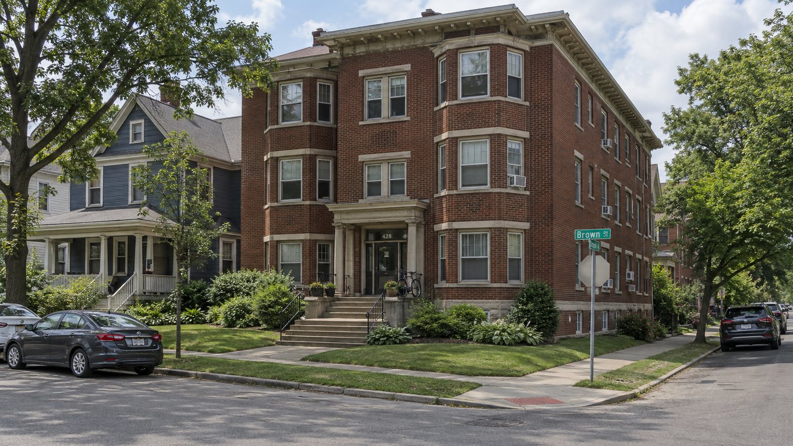 Older apartments and houses in the Dayton moving plan Three-story brick apartment building beside a timber house, with shared front steps and connected sidewalks