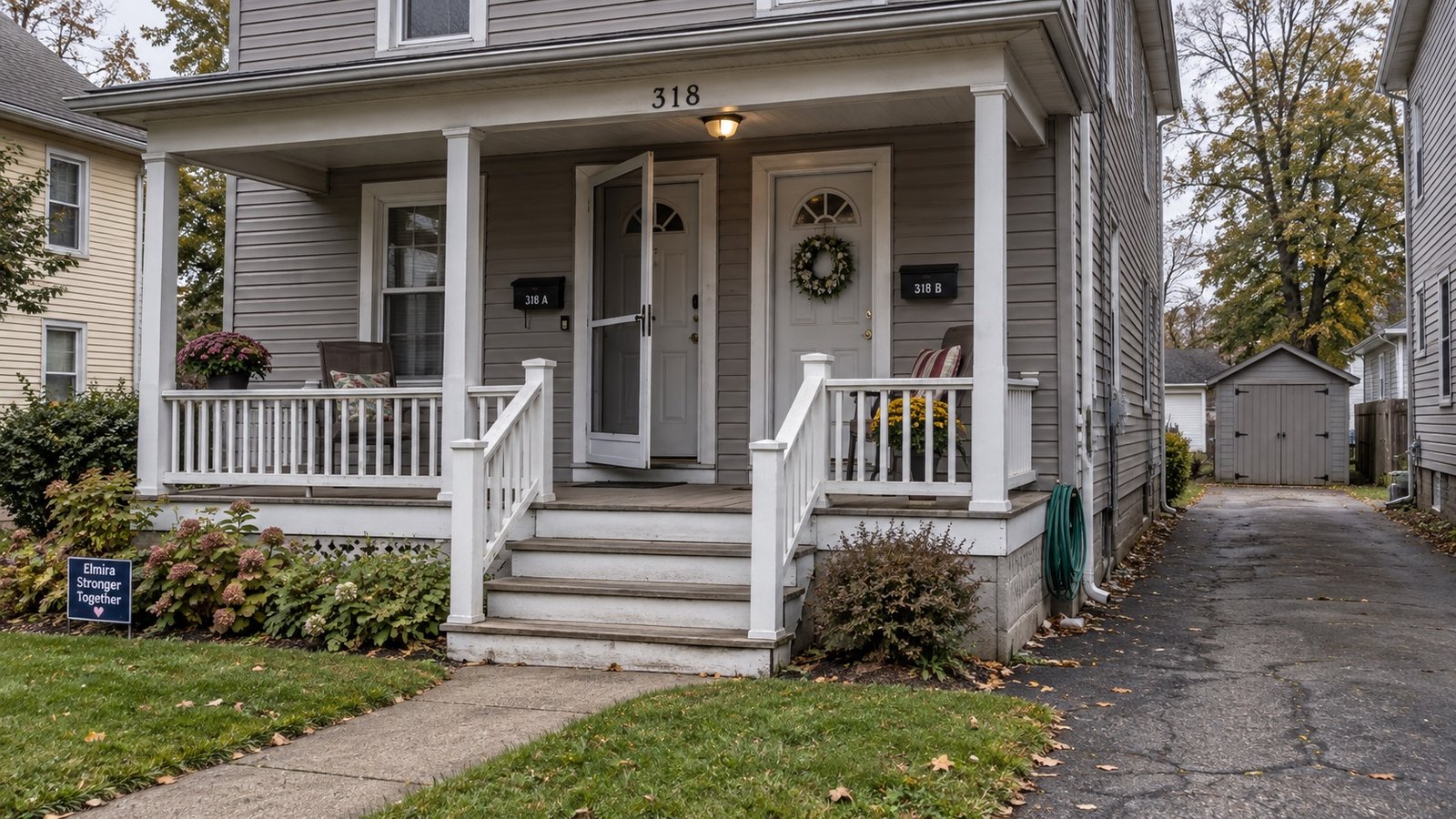 An older frame double with a shared porch and a narrow side driveway.