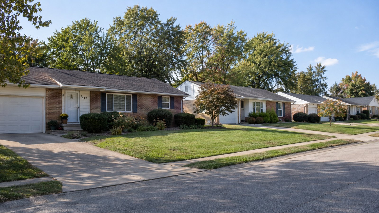 Check the outside approach Low brick homes and lawns beside a connected residential street and driveways.
