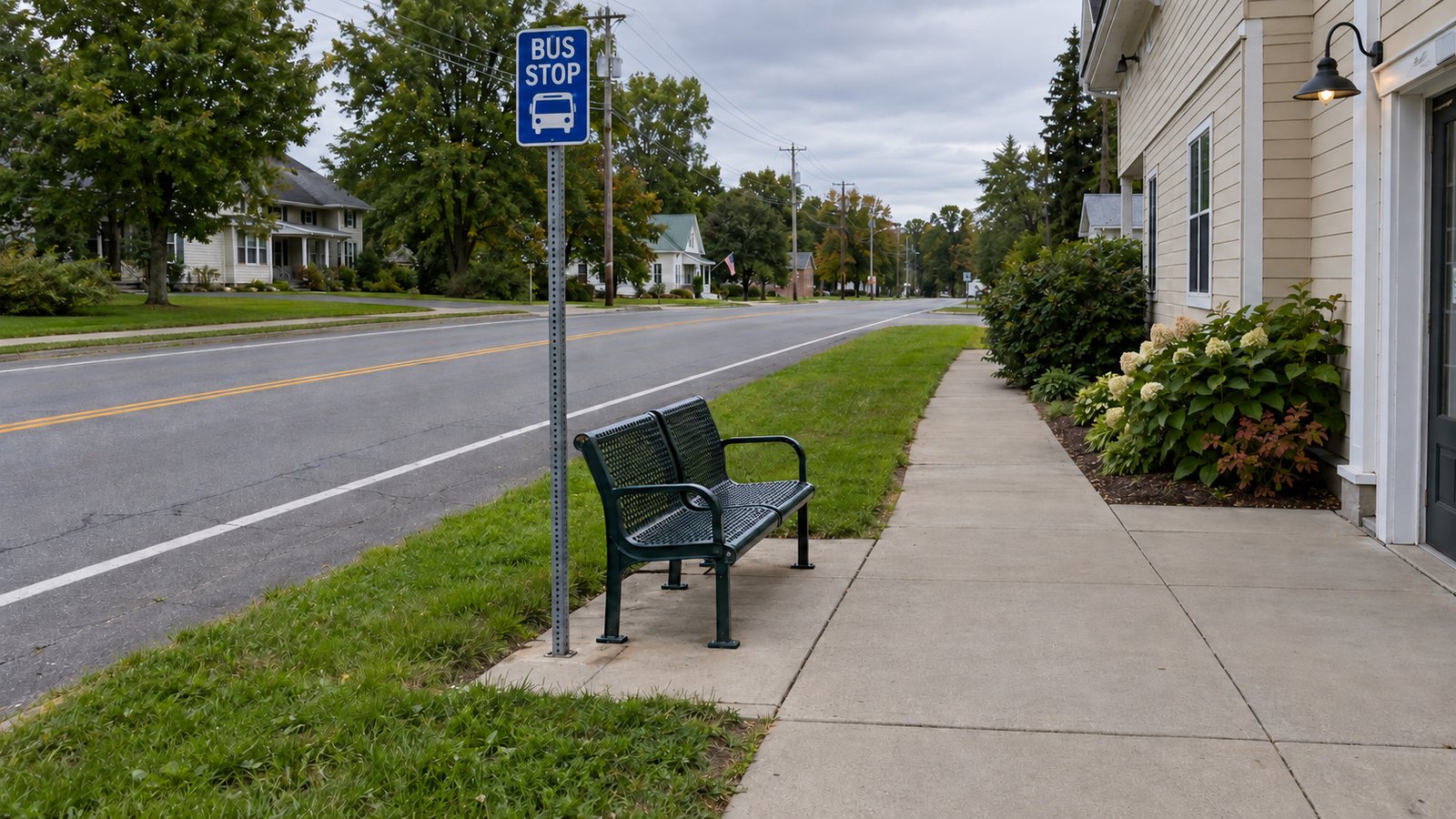 Planning a bus journey Bus stop sign and a two-seat bench on a paved pad beside a village sidewalk and grassy roadside verge