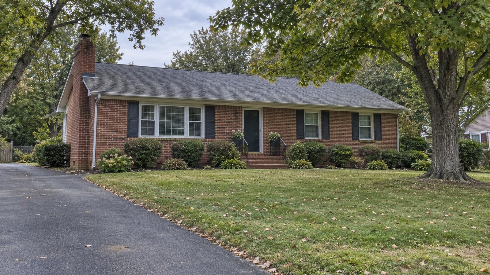 See the home and usable approach A complete modest brick house with a low roof, broad lawn and an asphalt drive.