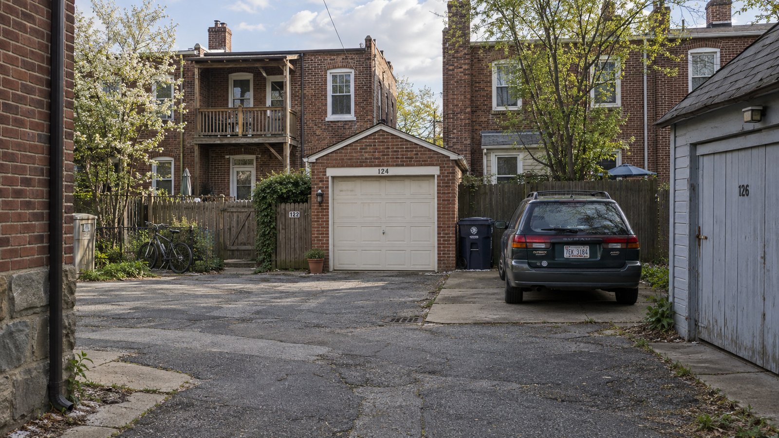 Rear access, garages and the full household inventory Rear alley beside brick rowhouses, individual garages, garden gates and a station wagon on a private parking pad