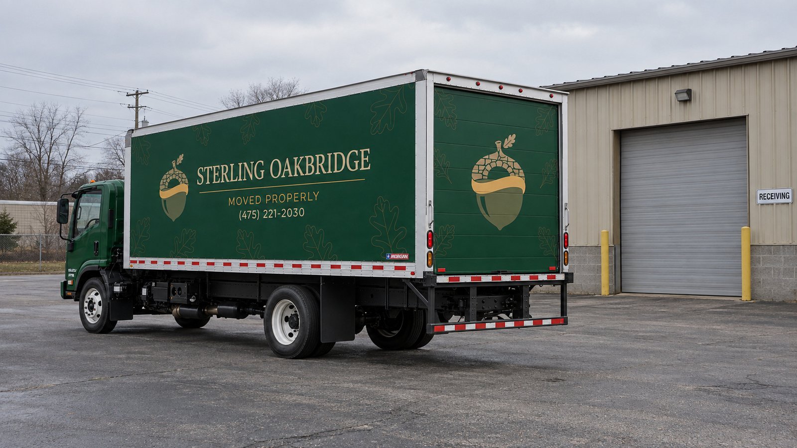 Green Sterling Oakbridge box truck parked in a paved receiving yard beside a closed roll-up door.
