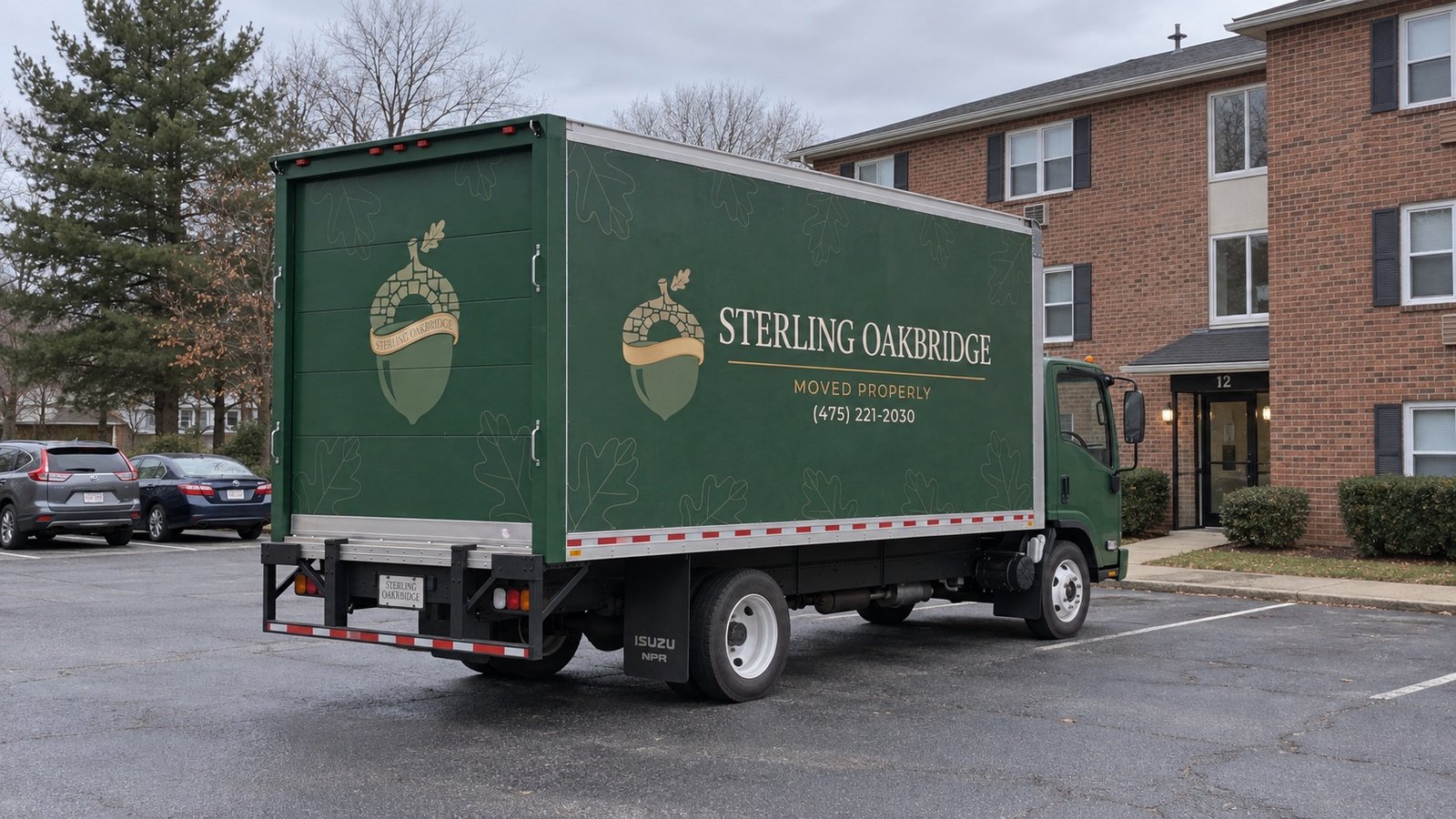 Planning space around the moving vehicle A green Sterling Oakbridge box truck parked in a paved court beside a brick apartment building