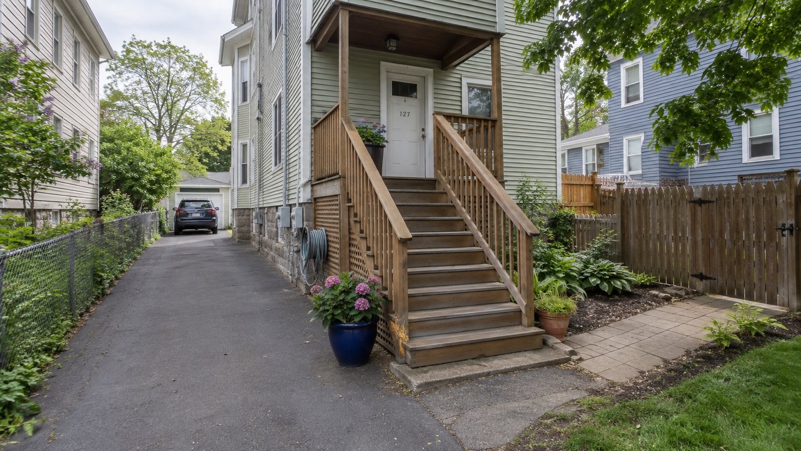 A wood-frame triple-decker house with a side driveway and stacked rear porches.
