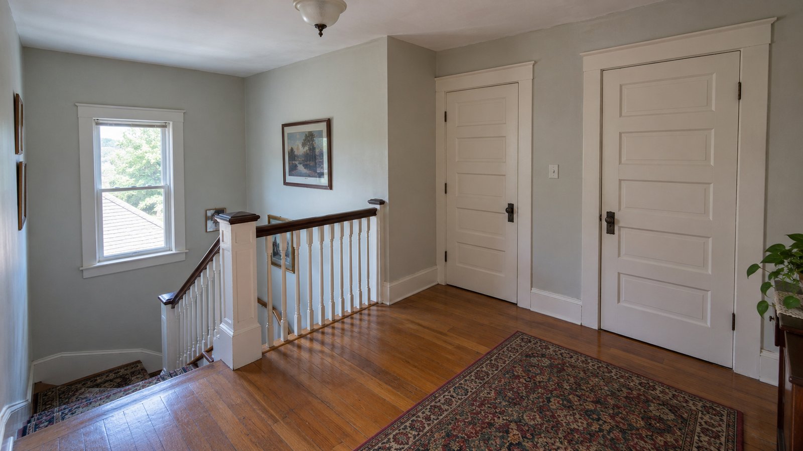 Trace the stair and turning space An empty upper-floor landing with two closed bedroom doors, balustrade and a stair head.