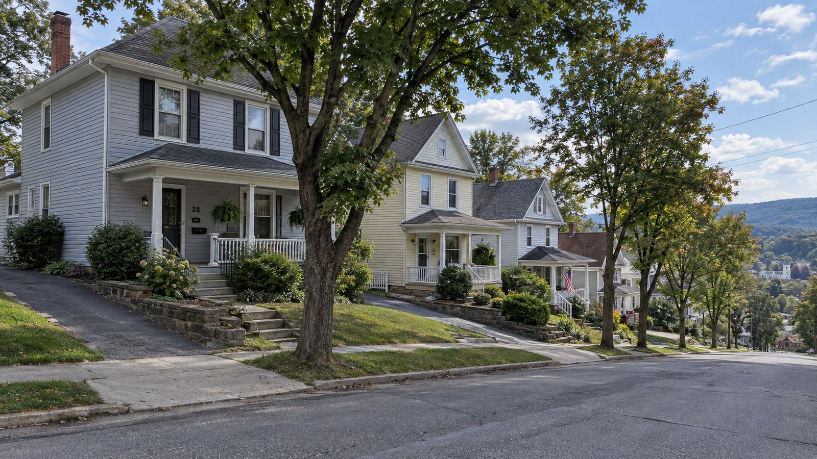 Review the receiving address A gray two-story house with a covered porch, chimney, front walk and driveway on a sloping residential street.