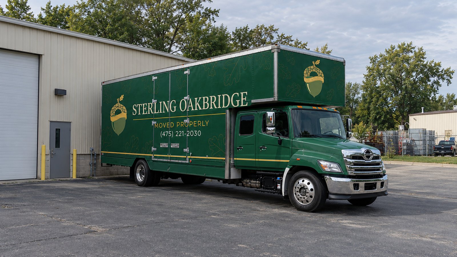 Space for the whole vehicle A green Sterling Oakbridge long-nose Hino box truck parked on a paved apron beside a commercial workshop.