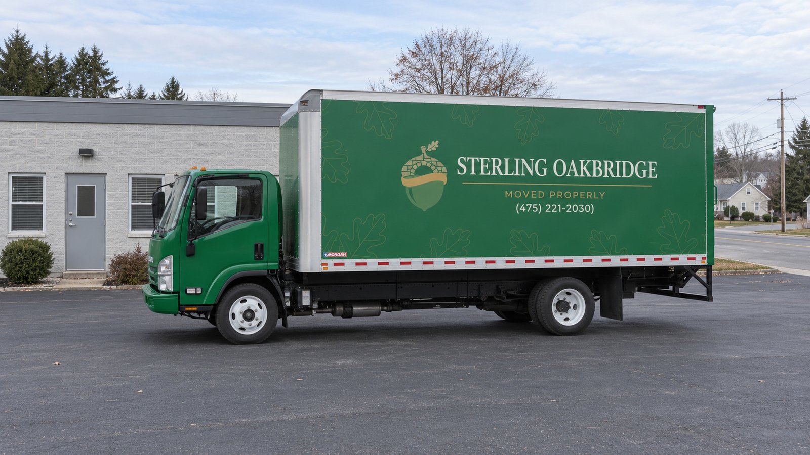 Confirm a usable truck position A whole green Sterling Oakbridge Isuzu NPR16 on an off-street commercial asphalt apron.