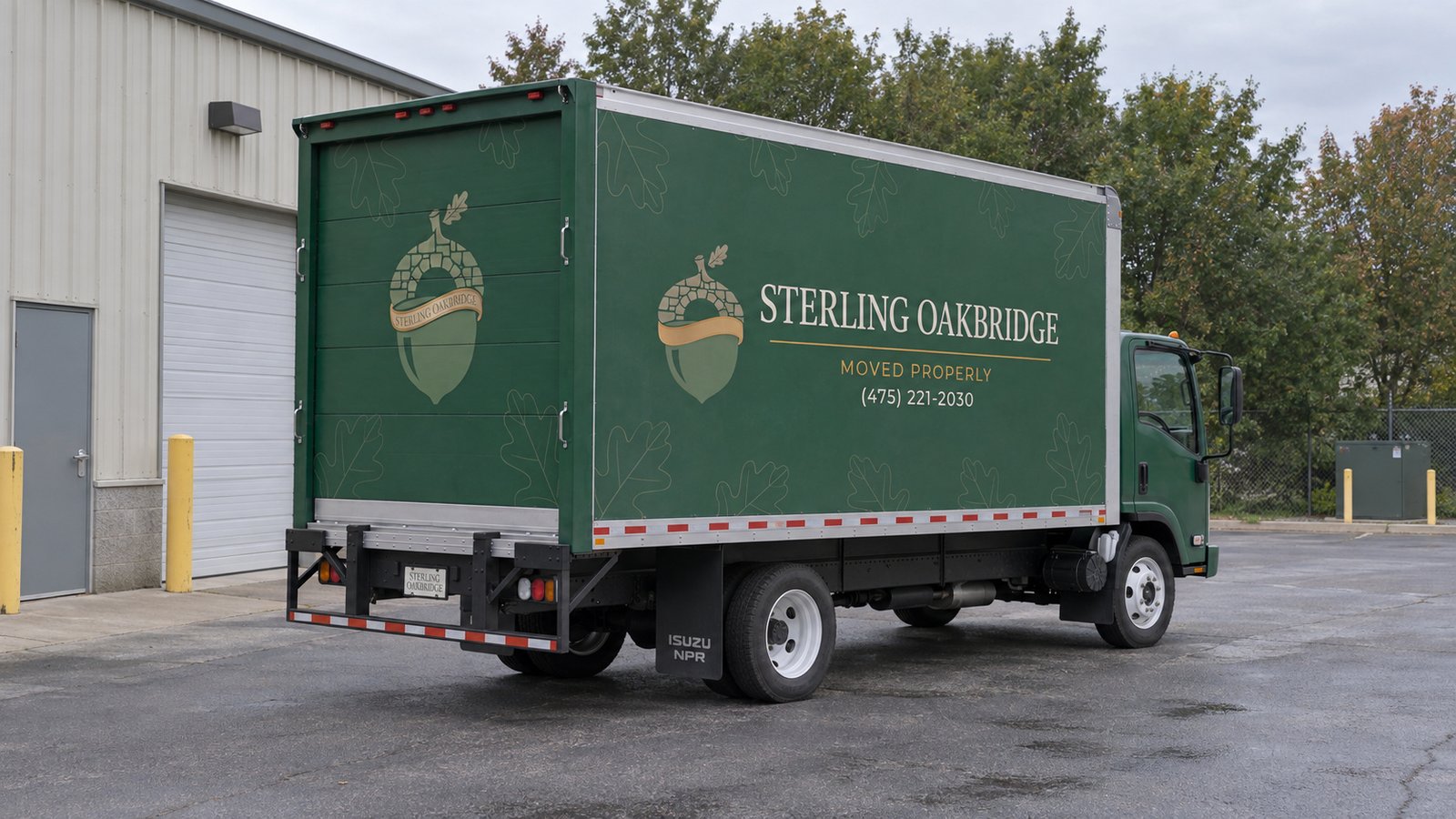 Confirm the truck position A complete green Sterling Oakbridge Isuzu NPR20 moving truck on a level paved receiving apron.