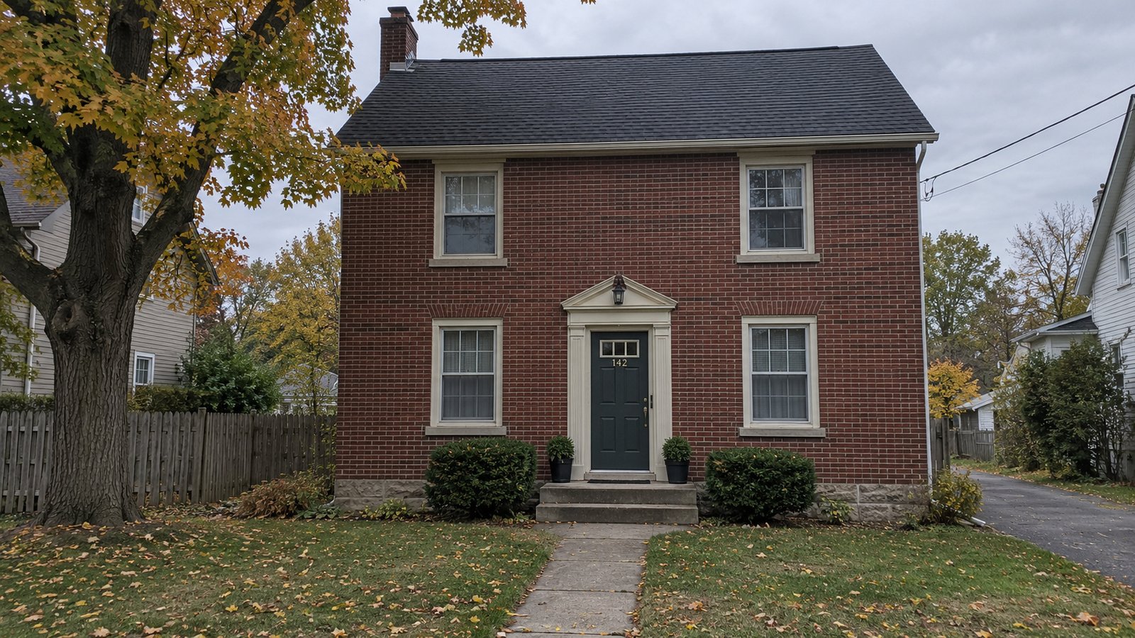 A home and its approach Two-story redbrick house with dark roof, front steps and a walkway in autumn