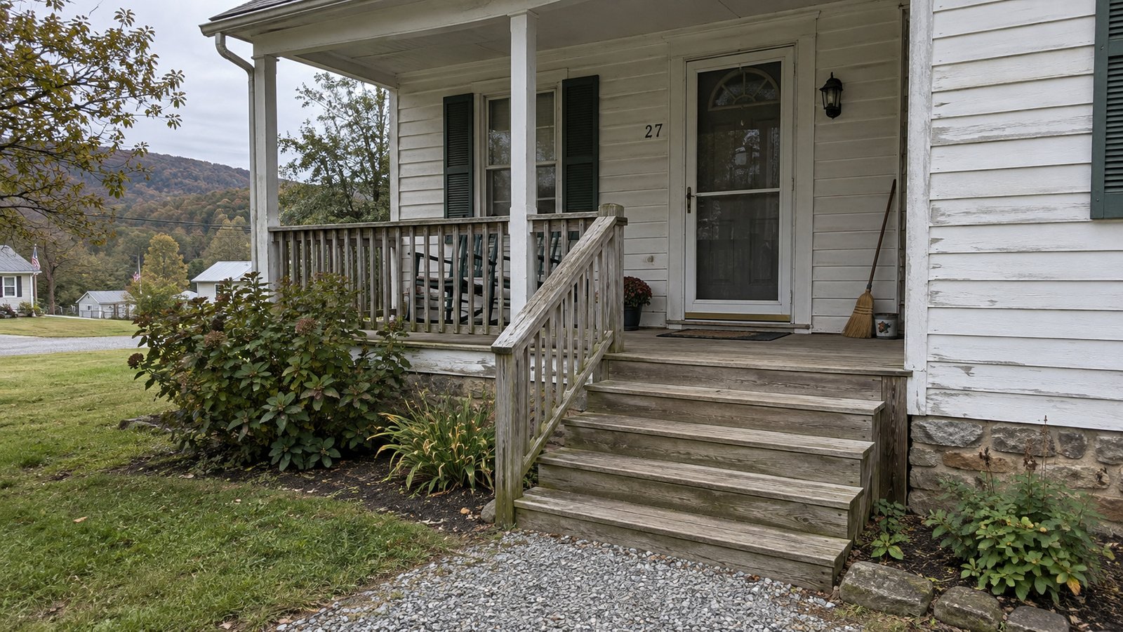 The porch carrying route Weathered white clapboard porch with a closed storm door, four broad steps and a wooden handrail.