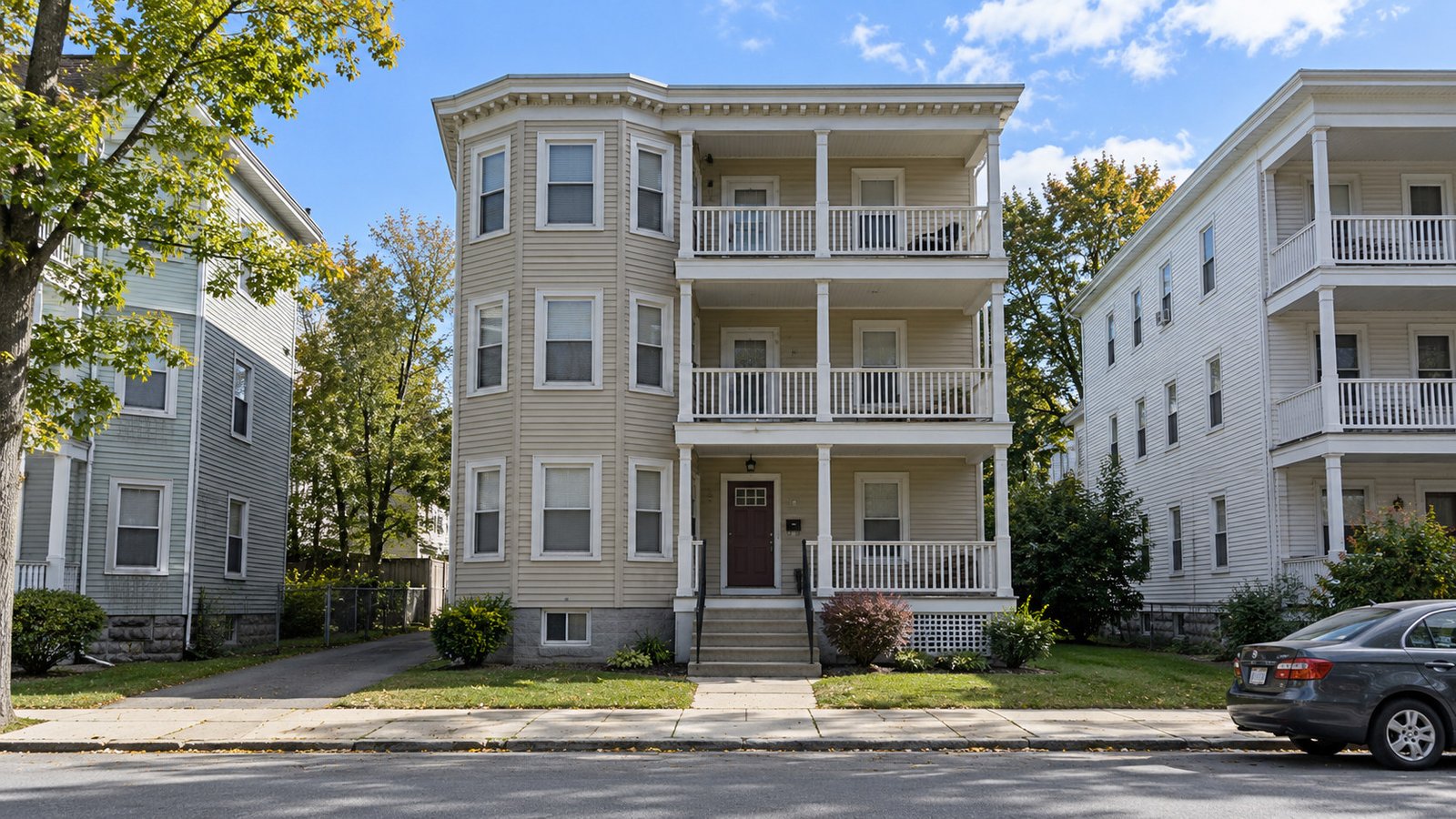 Three-decker entrance and unit access Wood-clapboard three-decker with stacked porches, a short front stair and clear shared entrance approach