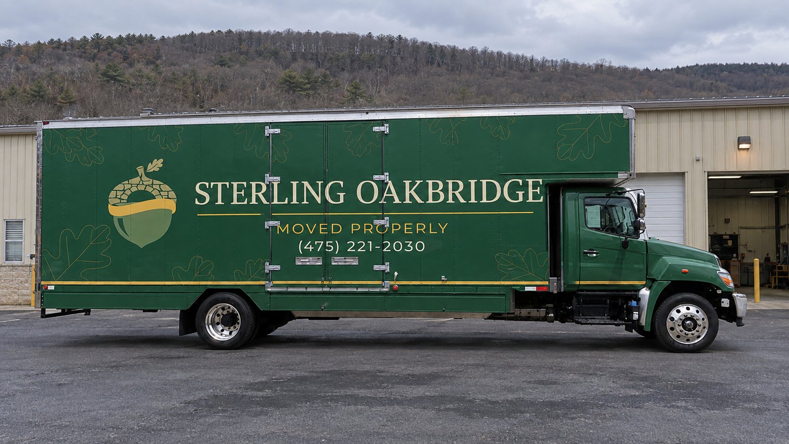 Space for a larger moving vehicle A green Sterling Oakbridge Hino box truck in side profile on a workshop forecourt