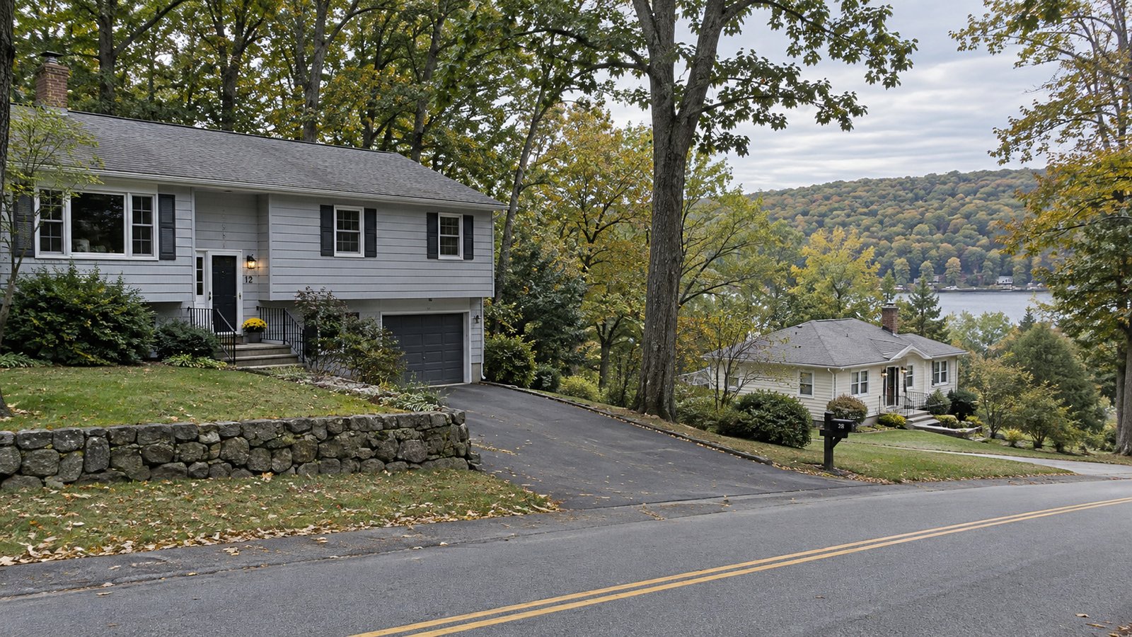 Planning a Mahopac residential move Two hillside houses with paved driveways, stone retaining walls and a glimpse of a lake