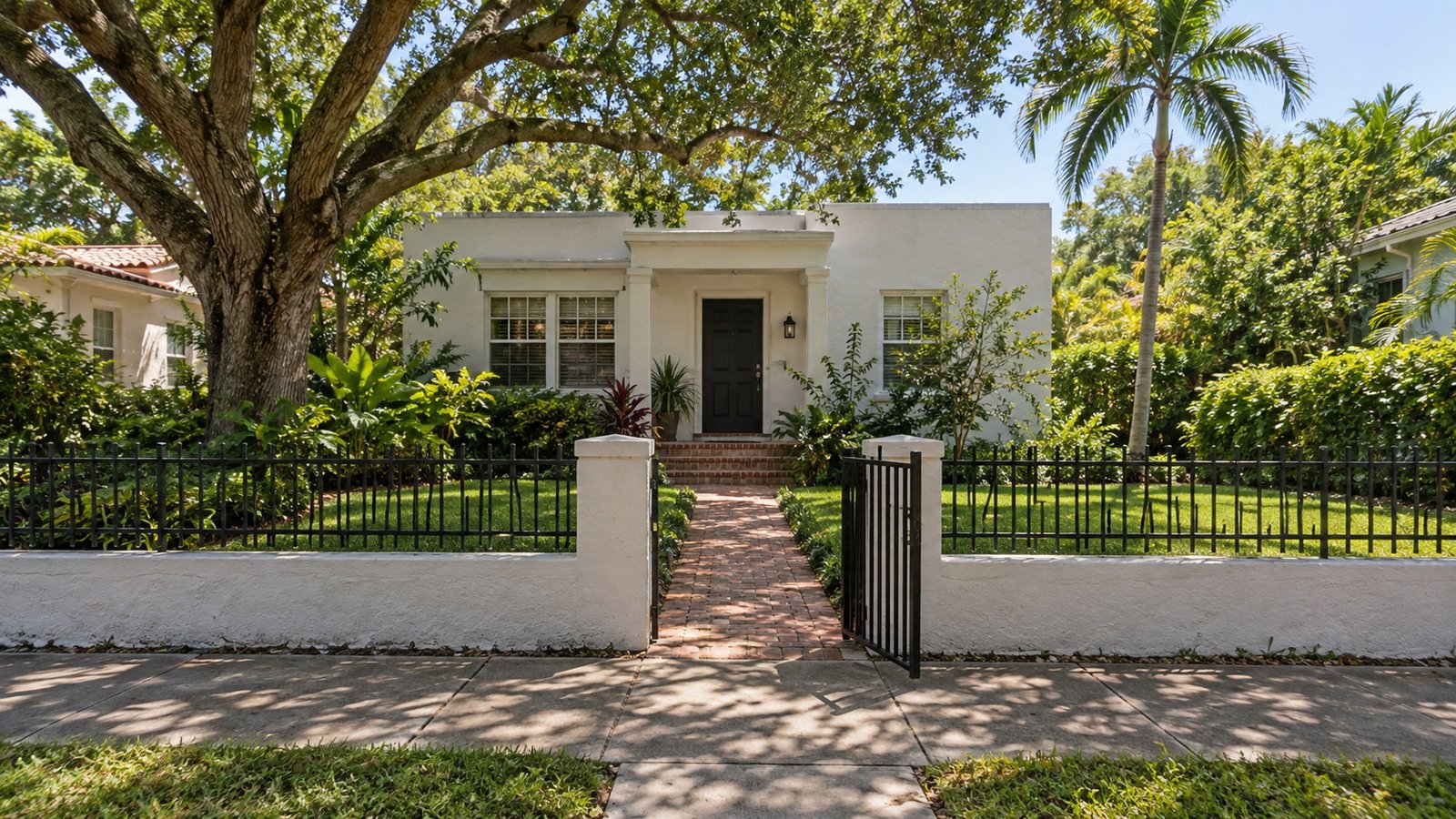 Gate, approach and raised porch White stucco house behind an open metal gate, with a narrow brick path leading to porch steps and a closed front door