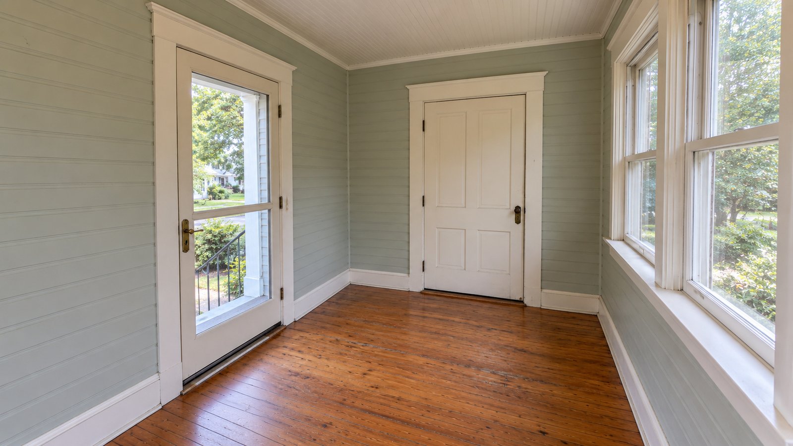 The turn inside an enclosed porch Glazed outer door and solid inner door on adjoining walls of an enclosed porch with a clear wooden floor