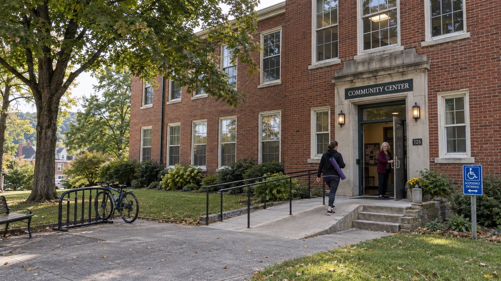 People entering a brick community center with a clear approach, steps and a bicycle rack