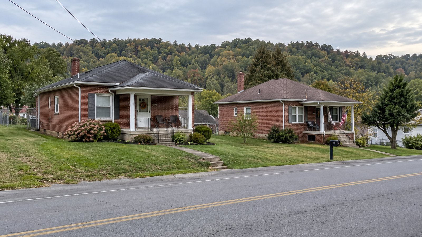 Two whole single-story brick homes with separate porches beside a road