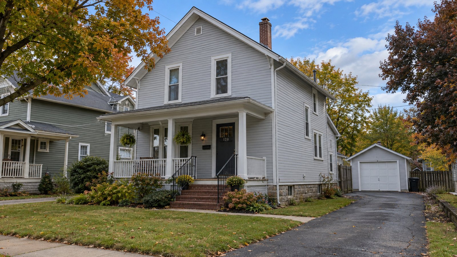 A home and its approach Two-story pale gray clapboard house with a covered front porch, brick steps and a paved drive to a detached garage