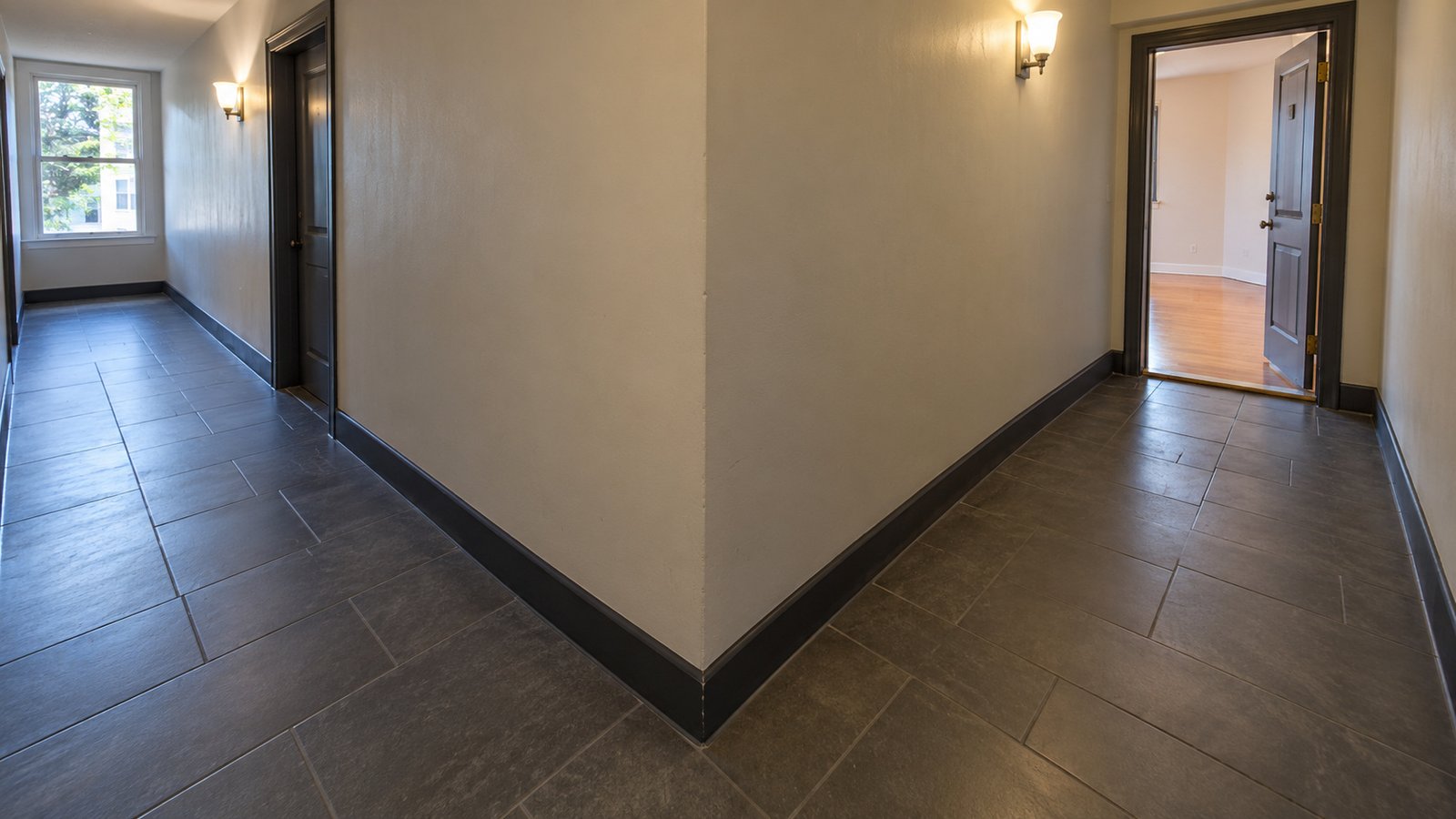 The turn before the receiving door Two clear tiled corridor arms around an outside corner, with an open receiving doorway at right.