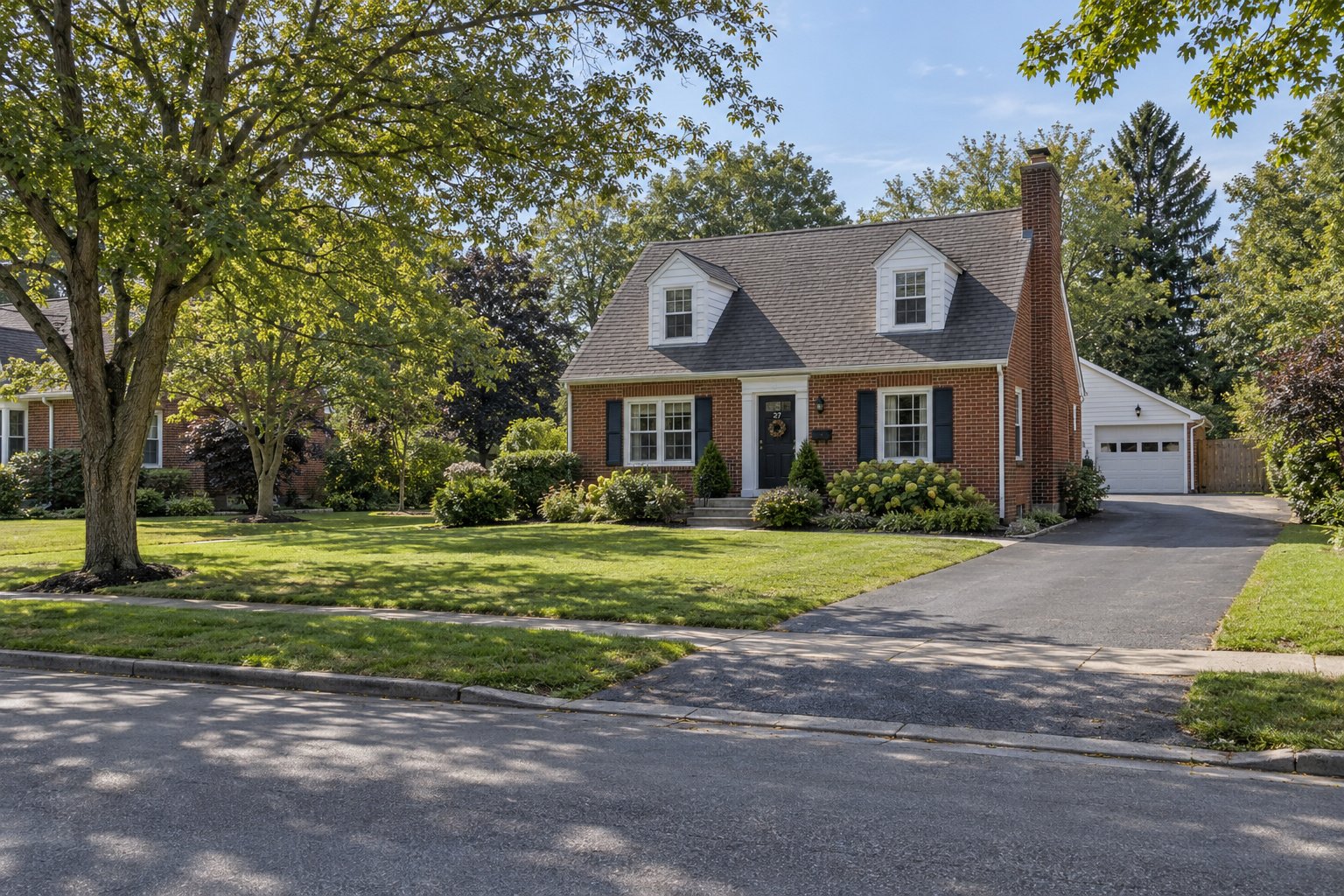 Inspect the property approach A complete modest red-brick house with a chimney, front entrance and connected paved driveway beside a quiet residential lane.