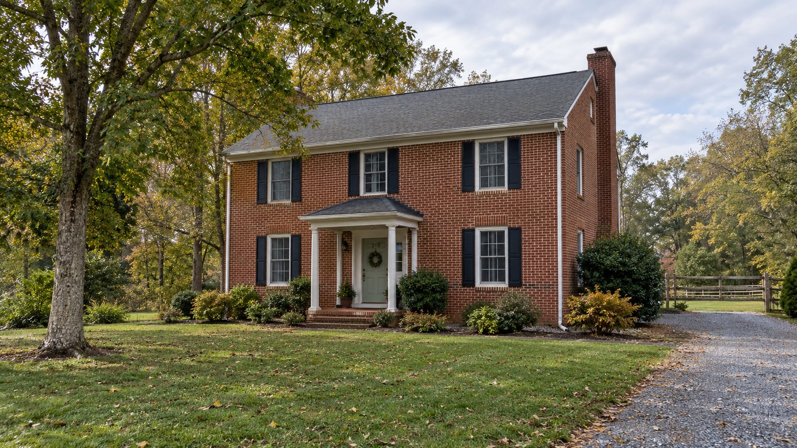Review the receiving property A complete red-brick two-story home with a pale front door, short porch, lawn and gravel driveway.
