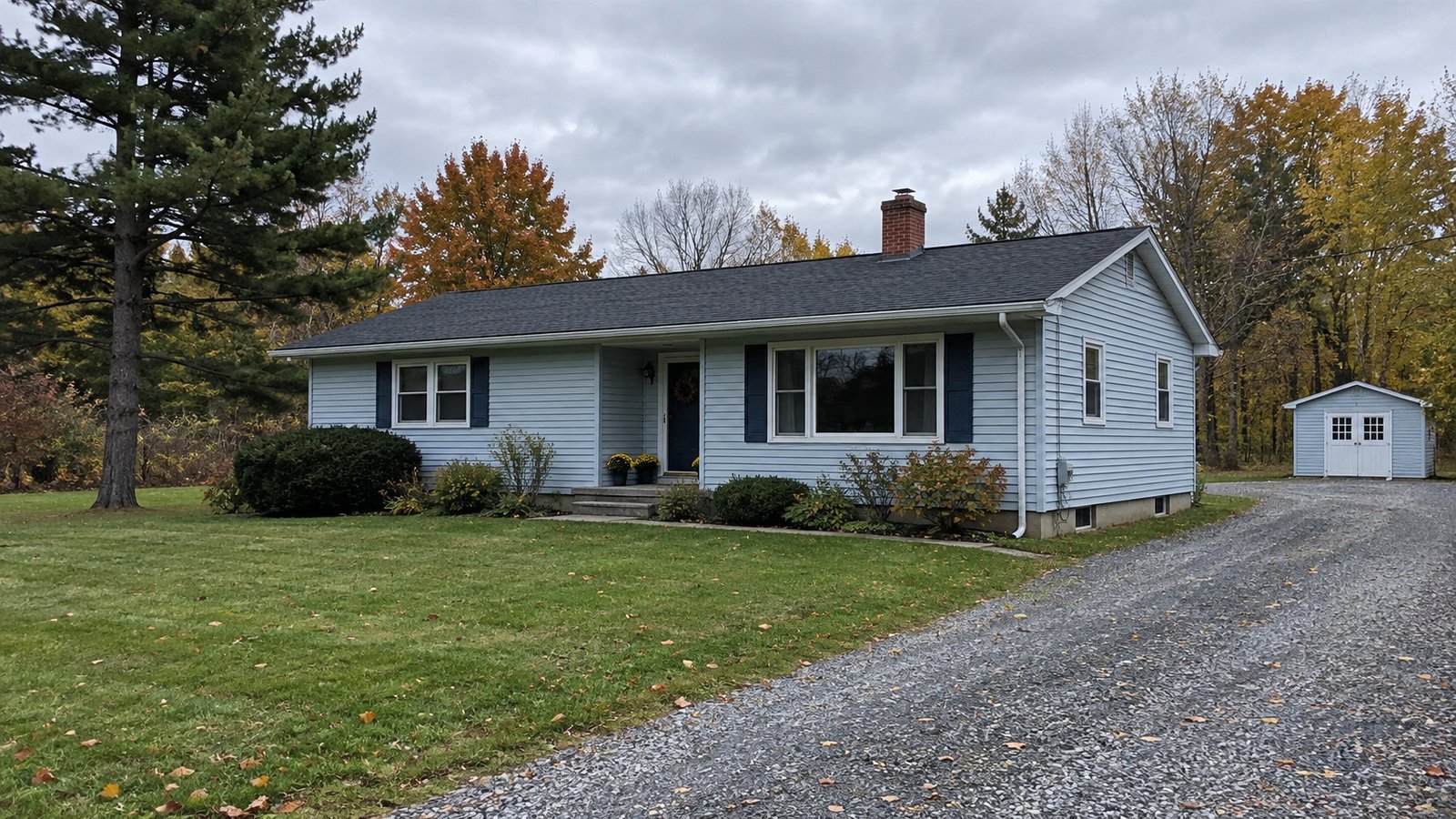 Single-story home and gravel driveway Pale blue single-story house with a recessed entrance, lawn and gravel driveway