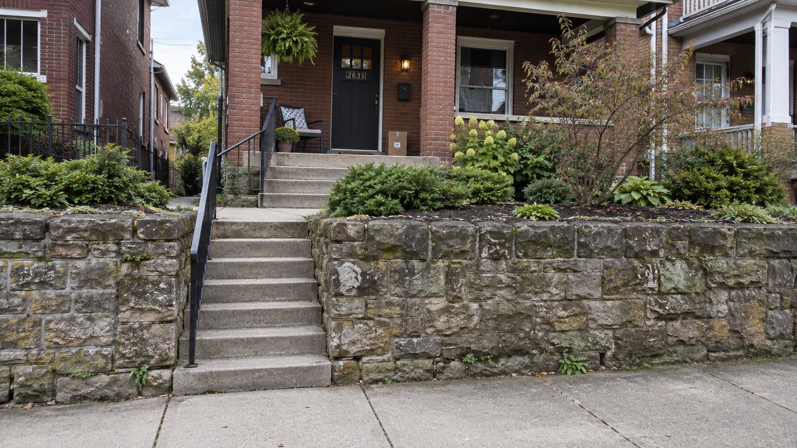 An older house above the street with outdoor steps and a retaining wall.