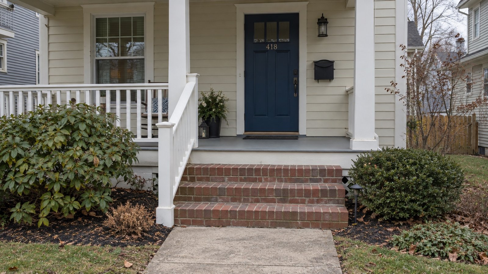 Blue front door, white porch railing and brick entrance steps