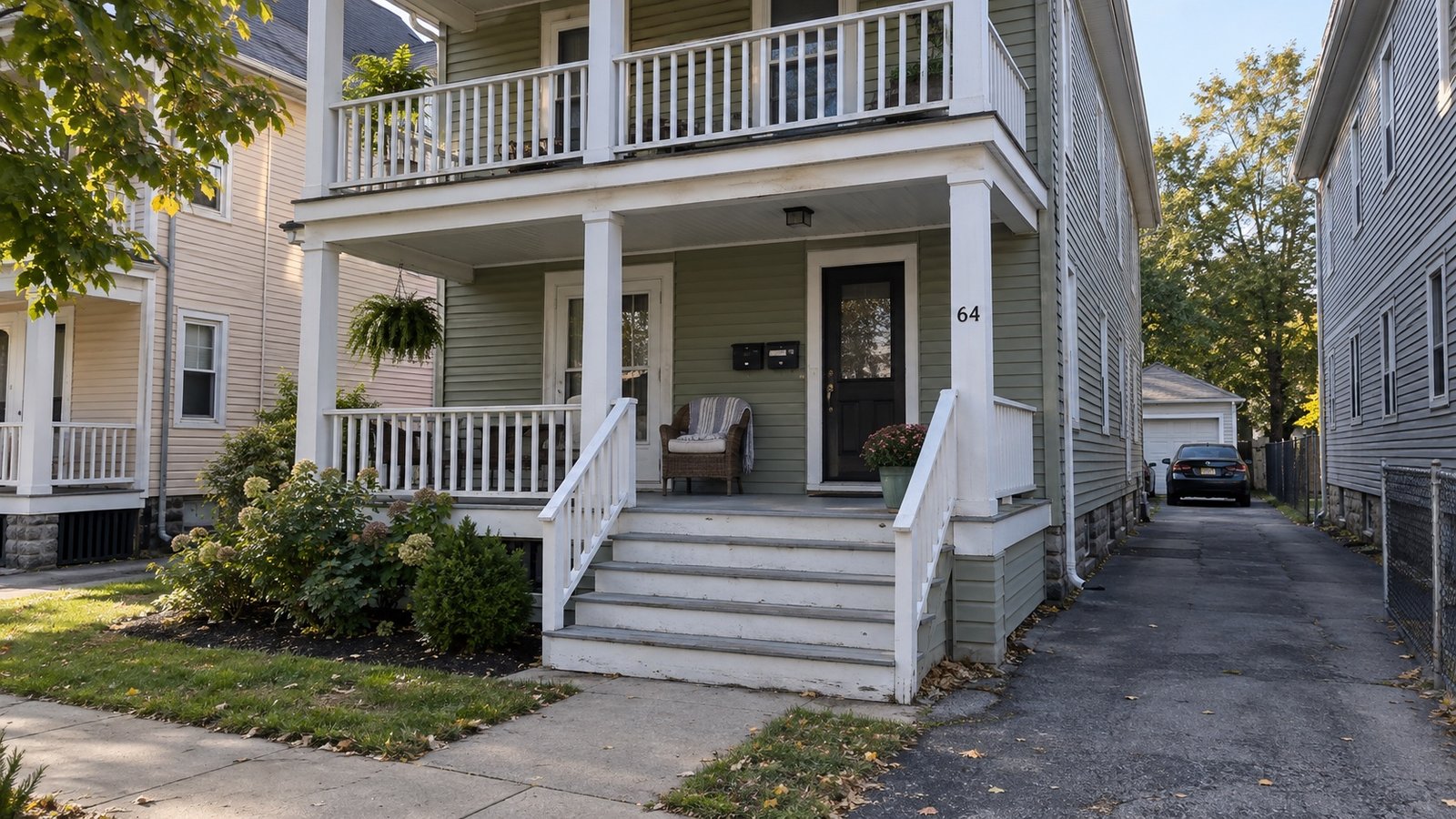 A two-family frame house with stacked front porches and a narrow side driveway.