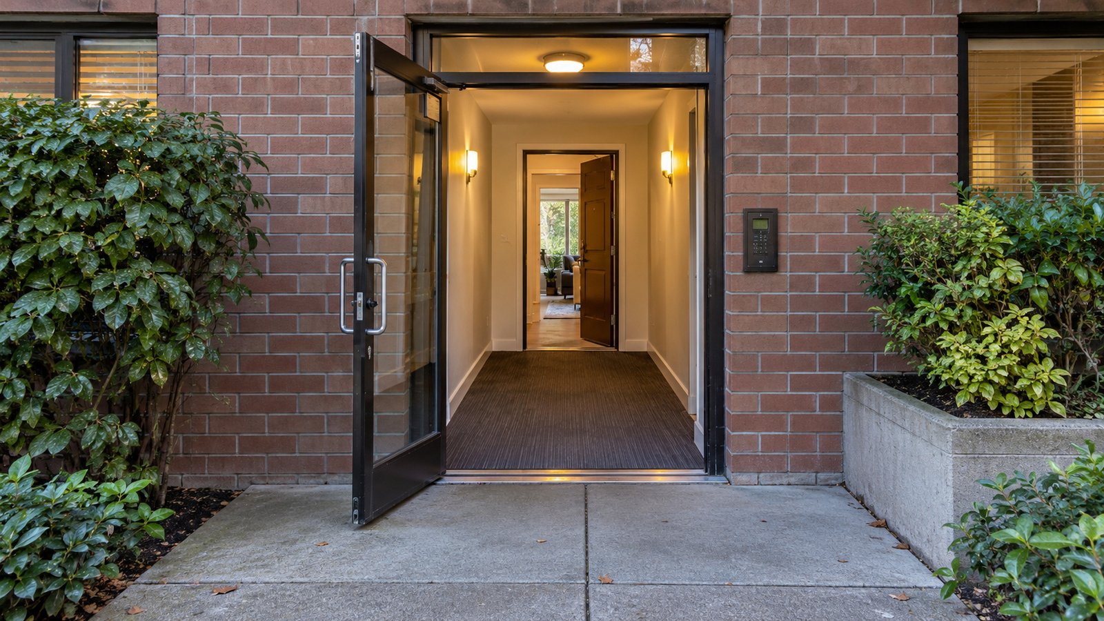 A complete brick condominium entrance opens through a short hallway to another open doorway. A complete brick condominium entrance opens through a short hallway to another open doorway.